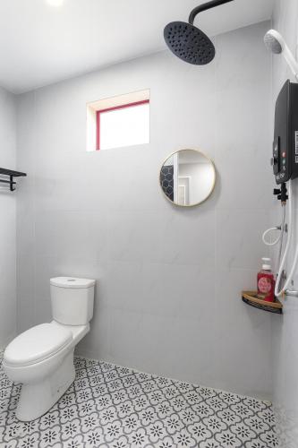 a white bathroom with a toilet and a mirror at De'5 Tiny House , Besut in Kampong Kubang Bemban