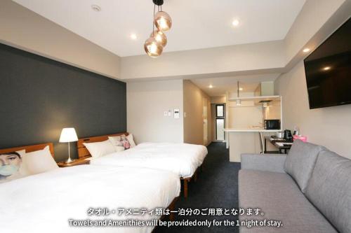 a hotel room with two beds and a couch at ZONK HOTEL Nakasu in Fukuoka