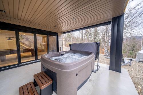 a large jacuzzi tub in a room with windows at Ski in - Ski out - SPA & Pool Table - Le Konect in Saint-Philémon