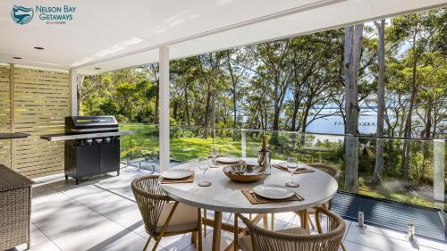 a dining room with a table and chairs on a patio at Woodlands Sunsets Soldiers Point - Whole Property in Soldiers Point