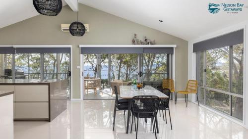 a kitchen and dining room with a table and chairs at Woodlands Sunsets Soldiers Point - Whole Property in Soldiers Point