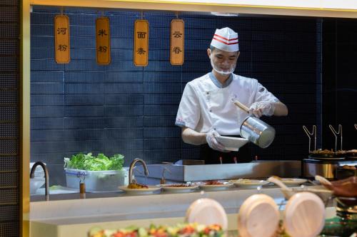 um chef de cozinha a preparar comida em Atour S Hotel Shenzhen Futian Port em Shenzhen