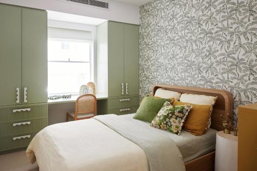 1 dormitorio con paredes verdes y 1 cama con almohadas en Beachfront Bliss at Clovelly, en Clovelly