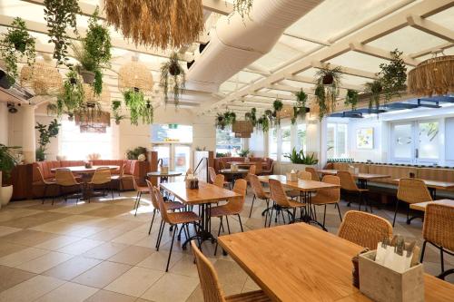 a restaurant with wooden tables and chairs and plants at Coogee Bay Hotel in Sydney