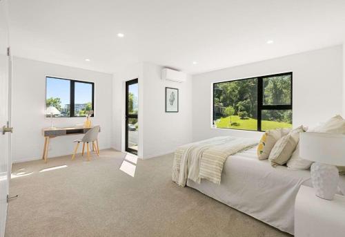 a white bedroom with a bed and a desk at Duo Duo in Auckland