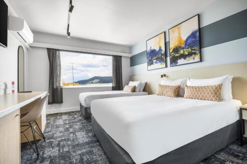 a hotel room with two beds and a desk at Nightcap at Burnie Townhouse in Burnie