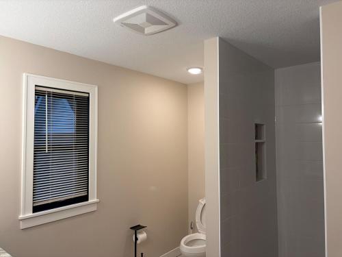 a bathroom with a toilet and a window at Luxurious Sweet Escape stunning custom Home! in Rochester