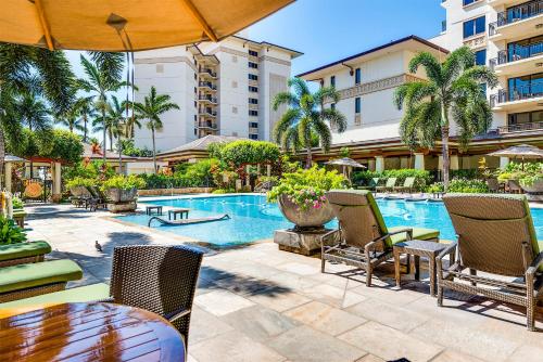 a pool at a resort with chairs and a table at TOP Floor Penthouse with Panoramic View - Ocean Tower at Ko Olina Beach Villas Resort in Kapolei