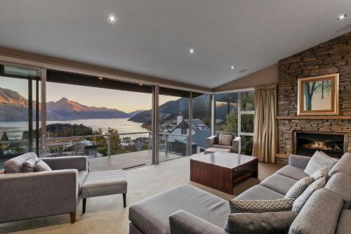 a living room with a fireplace and large windows at Remarkable Location Queenstown in Queenstown