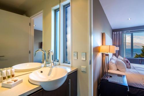 a bathroom with two sinks and a bed with a window at LakeRidge Queenstown by Staysouth in Queenstown