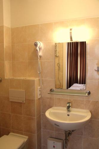 a bathroom with a sink and a mirror and a toilet at City Hotel Gotland in Berlin