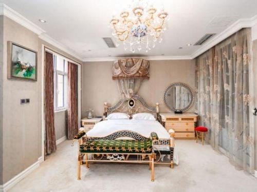 una grande camera da letto con un letto e un lampadario a braccio di Qingdao Danube International Hotel a Qingdao