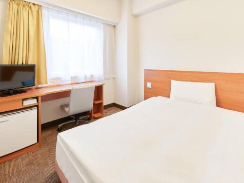a hotel room with a bed and a desk with a computer at Comfort Inn Ichinoseki Inter in Ichinoseki