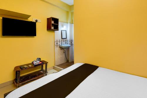 钦奈Super Hotel O Egmore Metro Station Chennai Formerly Harini Lodge的卧室里有一张床和一面黄色的墙