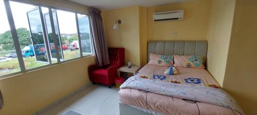 a small bedroom with a bed and a red chair at RELAX HOTEL in Sungai Petani