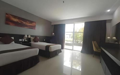 a hotel room with two beds and a window at Grand Hawaii Hotel Pekanbaru in Pekanbaru