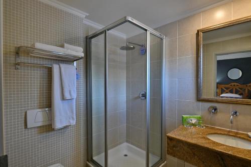 um banheiro com chuveiro e pia em Courtyard Hotel Rosebank em Joanesburgo