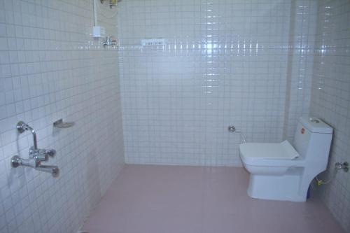 uma casa de banho em azulejos brancos com um WC e um chuveiro em Skytouch mud-house cottage em Jibhi