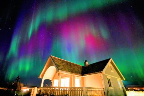 una casa con la aurora boreal en el cielo en BanPim Beachside Lofoten, en Ramberg