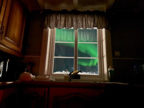 Una ventana de la cocina con vistas a la aurora boreal. en BanPim Beachside Lofoten, en Ramberg
