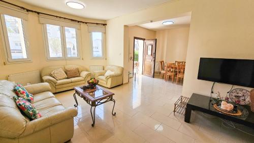 a living room with couches and a flat screen tv at Townbeach Villa with Private Pool in Voroklini