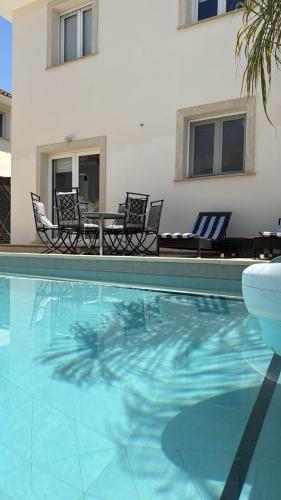 a pool with chairs and a table and a house at Townbeach Villa with Private Pool in Oroklini