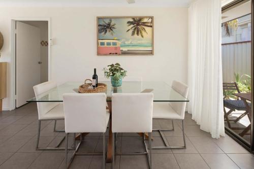 Golden BeachGolden Beach Bungalow - 500m to the beach的配有玻璃桌和白色椅子的餐厅