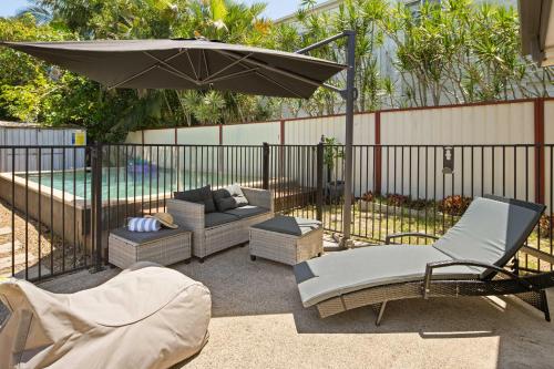a patio with an umbrella and chairs and a couch at Golden Beach Bungalow - 500m to the beach in Golden Beach