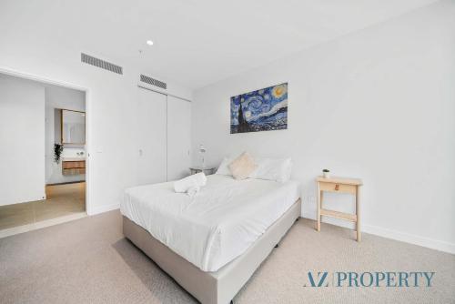 a white bedroom with a bed and a table at Metro Nest Light-Filled 1BR in CBD in Perth