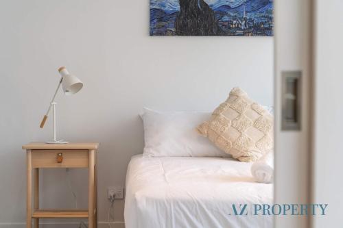 a bed with white sheets and a lamp on a table at Metro Nest Light-Filled 1BR in CBD in Perth