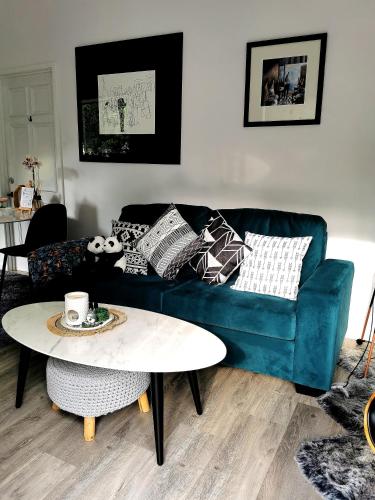 a living room with a blue couch and a table at Oohlala - High ceiling Peaceful Relaxing Bushland view in Mount Tamborine