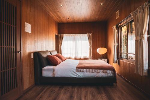 a bedroom with wooden walls and a bed with a window at Karabiner House Myoko in Myoko