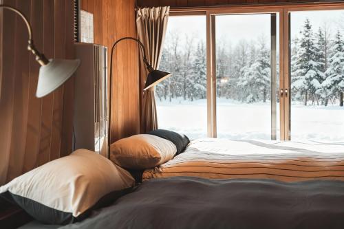 a bedroom with a bed and a window with snow outside at Karabiner House Myoko in Myoko