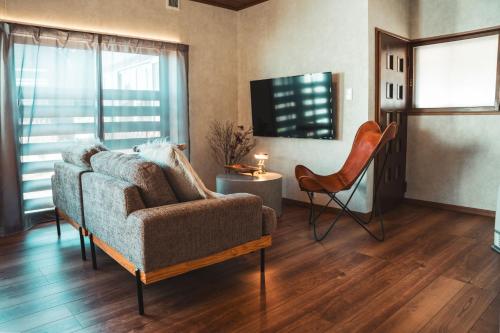a living room with a couch and a chair at Karabiner House Myoko in Myoko