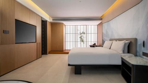a bedroom with a white bed and a flat screen tv at Holiday Inn Express Guangzhou Baiyun Airport T2 by IHG in Huadu