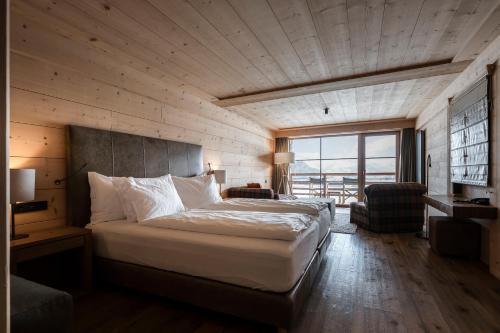 a bedroom with a large bed and a large window at ADLER Alpe in Alpe di Siusi