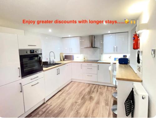a kitchen with white cabinets and a wooden floor at Westons Hideaway, 2 Bed, Free Parking, 6 mins walk to beach, in Weston-super-Mare