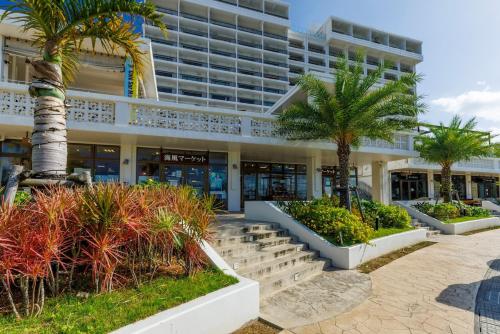 a building with palm trees in front of it at 本部町 最大12名宿泊可 無料駐車場2台付き 家族 グループに最適 Terrace Motobu in Motobu