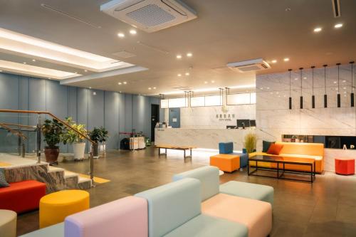 un vestíbulo de oficina con mesas y sillas coloridas en Arban City Hotel, en Busan
