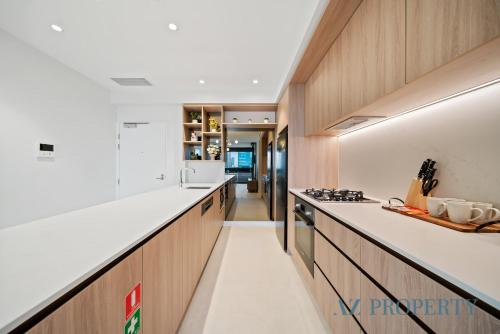a kitchen with white counter tops and wooden cabinets at Luxury Perth CBD Apartment with Pool & Gym - Sleeps 3 in Perth