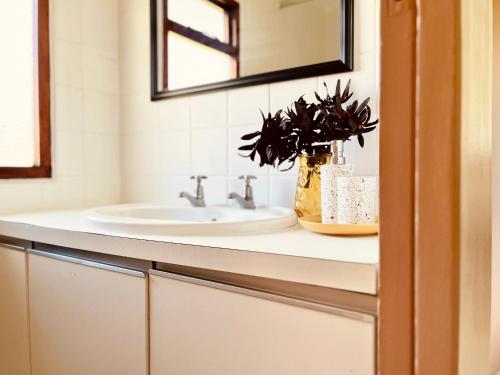 a bathroom with a sink and a mirror at Sandpiper Cottage in Fish Hoek