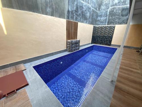 uma piscina com azulejos azuis num quarto em Sierra Villa Malang - Private Swimming Pool - 4 BR em Ngadipuro