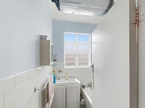 ダーバンにあるBeach view bnbの洗面台と窓のある白いバスルーム