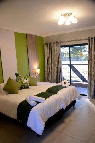a bedroom with a large bed with green walls at Green Side accommodation in Rustenburg