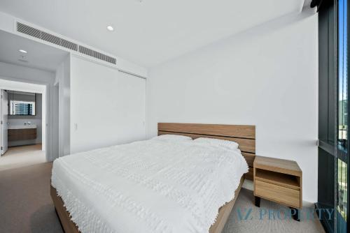 a white bedroom with a large bed and a table at Bright & Spacious 2BR in Prime CBD Location in Perth