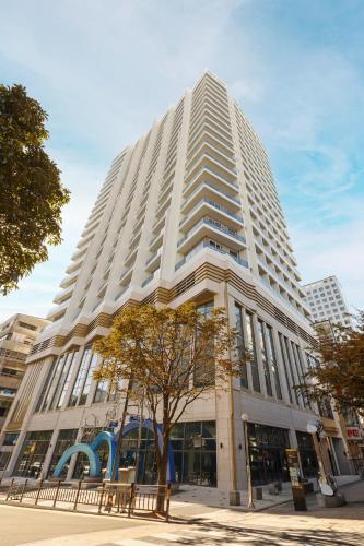 a tall white building with a tree in front of it at New CZ Nampo Hotel in Busan