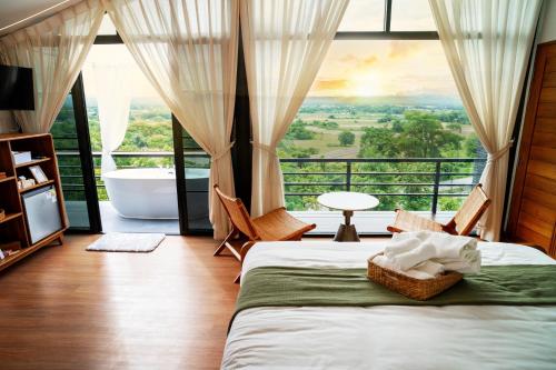 ein Schlafzimmer mit Badewanne und Bett mit Aussicht in der Unterkunft โรงแรมม่านฟ้า in Ban Na Tho