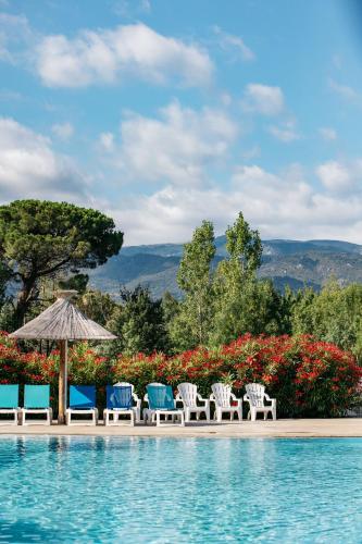 a group of chairs and an umbrella next to a swimming pool at Camping Les Pins - Bord de mer in Argelès-sur-Mer