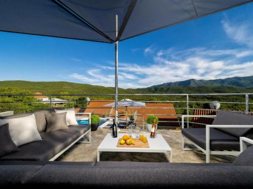 a patio with a couch and a table and an umbrella at Villa Vito - with heated pool, whirlpool, gym in Šarići