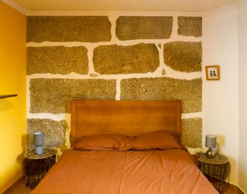 Bett in einem Zimmer mit einer Steinmauer in der Unterkunft Quinta Sarnadela - Spacious 3 bedroom house with mountain view in Oliveira do Hospital